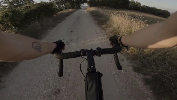 Biker riding downhill on dust road, Marche, Italy