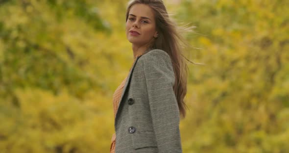 Back View of a Young Caucasian Woman in Checkered Jacket Standing in the Autumn Park