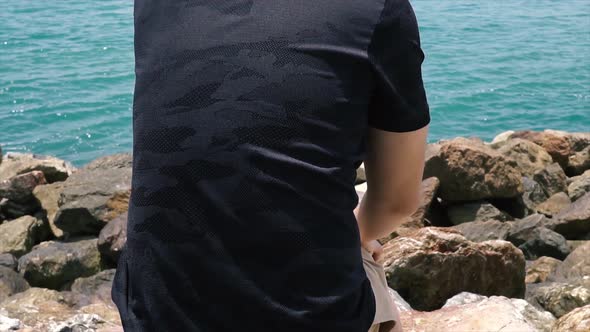 Young Man Sitting on the Seashore Beach and Enjoying Travel and Summer Vacation Moment