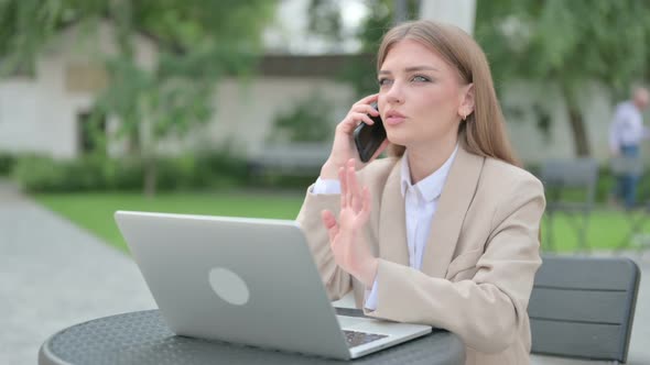 Young Businesswoman Talking on Phone in Outdoor Cafe