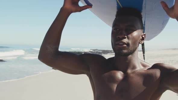 African American man holding a surfboard on his head