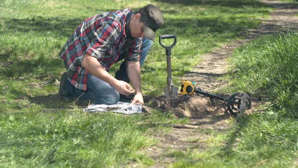 Male Treasure Hunter Pulls Out Old Coins Found on the Field with Metal Detector