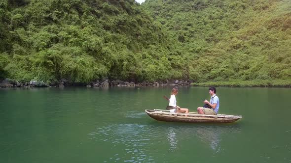 Drone Shows Girl and Man Rowing on Boat on Lake By Ha Long Bay