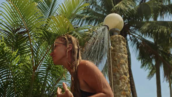 Woman Taking a Shower in Garden Near Hotel