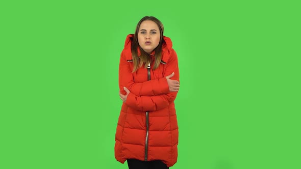 Lovely Girl in a Red Down Jacket Froze and Trying To Keep Warm. Green Screen