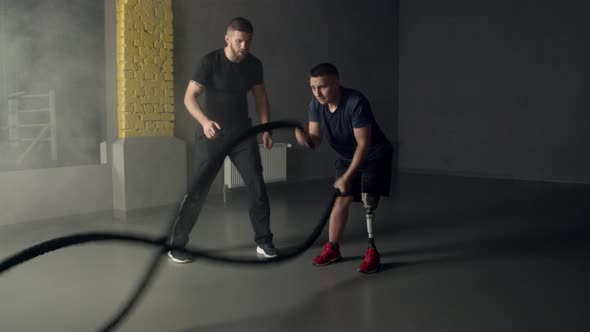 Young Man Having Prosthetic Leg Using Battle Ropes in Gym