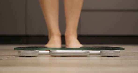 Female feet step on weighing scales. Weight loss concept