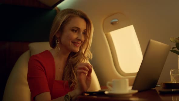 Cheerful Businesswoman Chatting Online on Private Jet Closeup