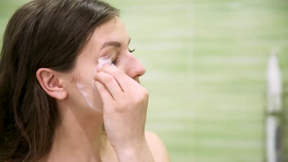 Girl Removes Makeup Using a Cotton Pad in a Green Bathroom