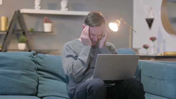 Casual Man with Laptop Having Headache on Sofa