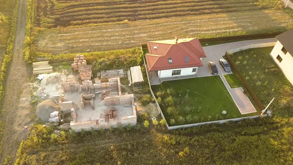 Top down aerial view of two private houses, one under construction with wooden roofing frame 