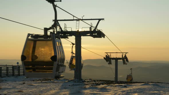 modern ski lift cabins move over white snow against hilltops