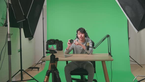 Camera Recording Asian Man Reviewing Camera Len On Green Screen With Professional Light Equipment