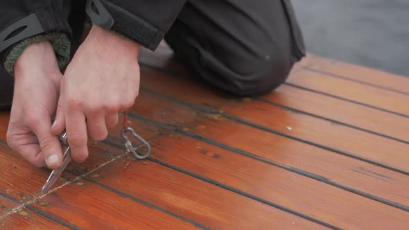 Hands young carpenter using knife to re old mastic from planking