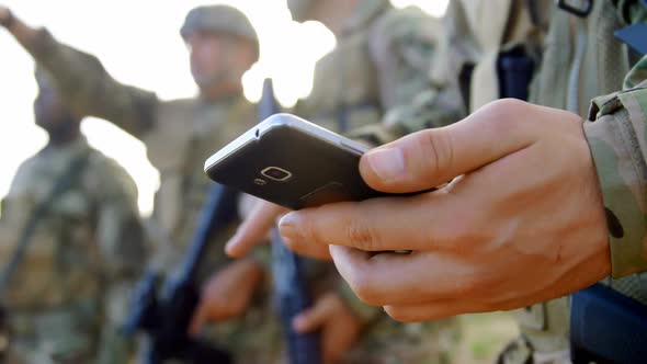 Mid section of caucasian military soldier using mobile phone during military training 4k