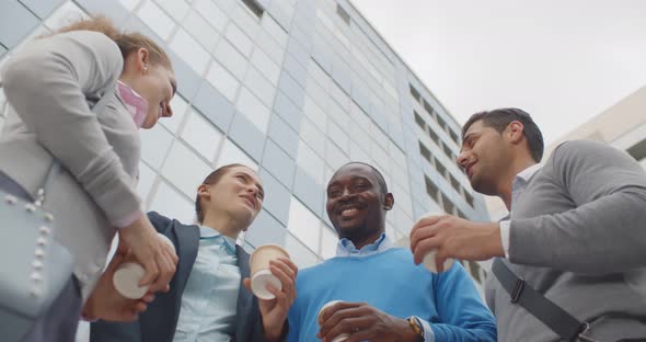Bottom View of Young Colleagues Outdoors Drinking Coffee Smiling and Chatting