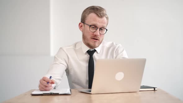 Business Man Having Online Conference or Business Discussion at Office and Writing Notes in Notepad