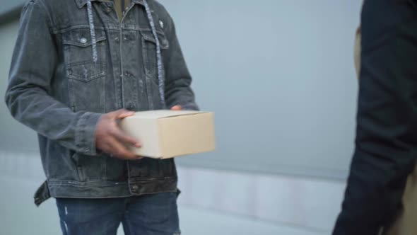 Male Courier Giving Parcel Box To Unrecognizable Female Client and Leaving