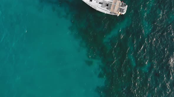 Sailboat on the Turquoise Sea Water. Nearby Vacationers Swim. Aerial Drone Shot