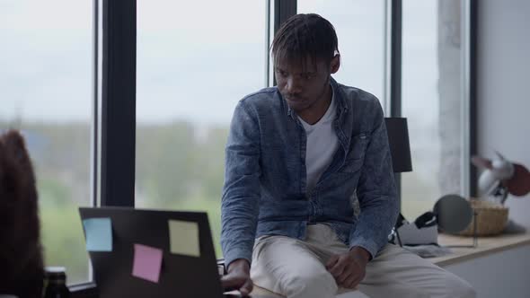 Portrait of Young Serious African American Man Checking Email on Laptop Drinking Morning Juice