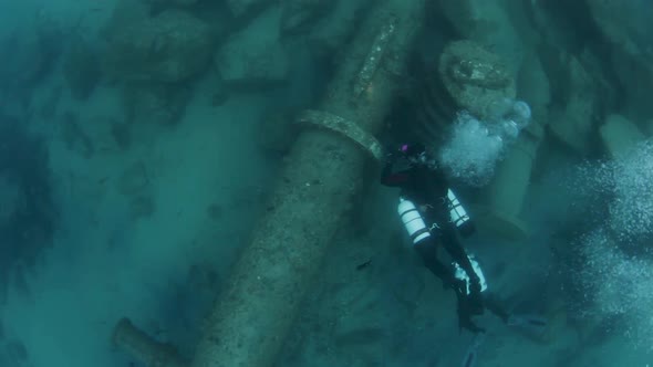 Scuba divers exploring an underwater pipeline sitting on the bottom of the ocean