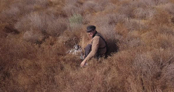 a man in the field training with his falcon that caught a pigeon