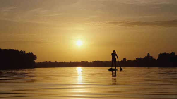 Female Silhouette on Paddle Board at Sunset