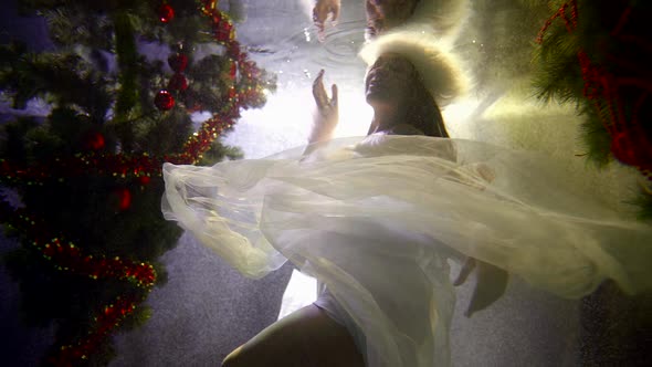 Woman Looks Like Snow Queen Is Floating Under Water in Pool in Christmas Decorations