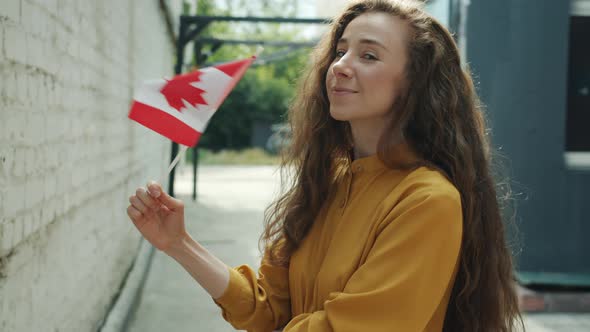 Portrait of Happy Young Lady Waving Canadian Flag Smiling Standing Outdoors in City