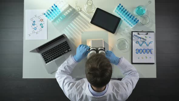 Laboratory Worker Studying Sample Under Microscope, Doing Experiment, Top View