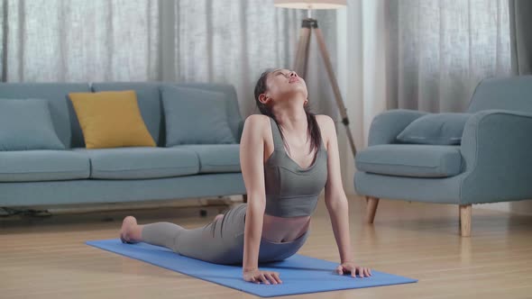 Asian Female In Sports Clothes Training On A Yoga Mat, Doing Upward Facing Dog During Workout