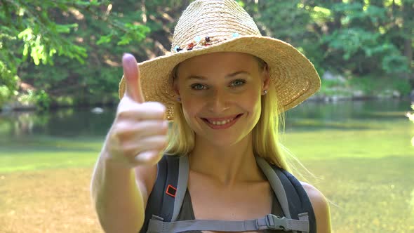 A Young Beautiful Woman Shows a Thumb Up To the Camera with a Smile in a Forest