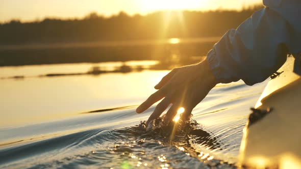 Man Puts Fingers Down Lake Kayaking Against Backdrop of Golden Sunset, Unity Harmony Nature