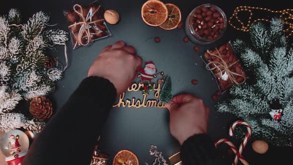 Christmas inscription, top-down view. Hands put a beautiful inscription on a table