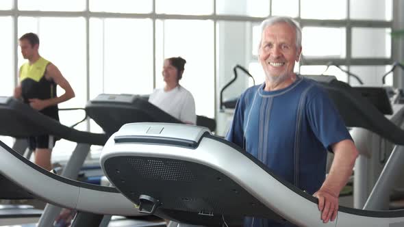 Smiling Aged Man Exercising at Gym.