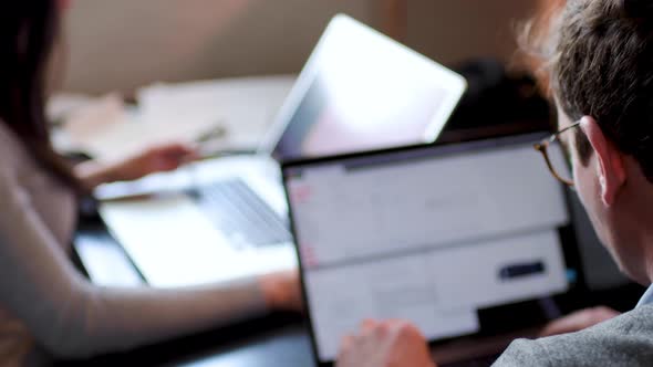 Colleagues looking at laptops in office, blurred