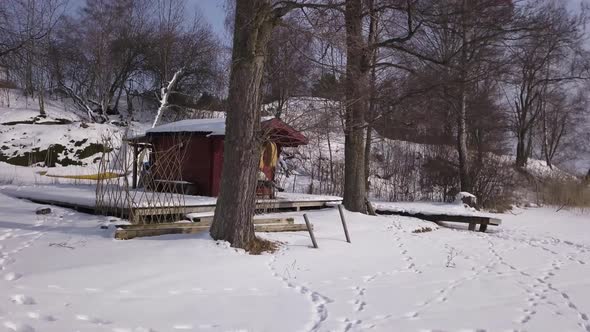 Smooth tracking aerial shot of rustic fishing cabin with lonely girl sitting and relaxing on porch.