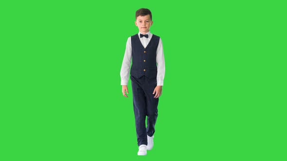 Little Boy in a Waistcoat and a Bow Tie Walking Looking Straight Ahead on a Green Screen, Chroma Key