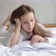 Portrait of a calm attractive young woman reading a book in the bed - VideoHive Item for Sale
