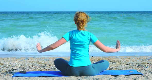 Young Woman Meditates on the Shore of the Ocean