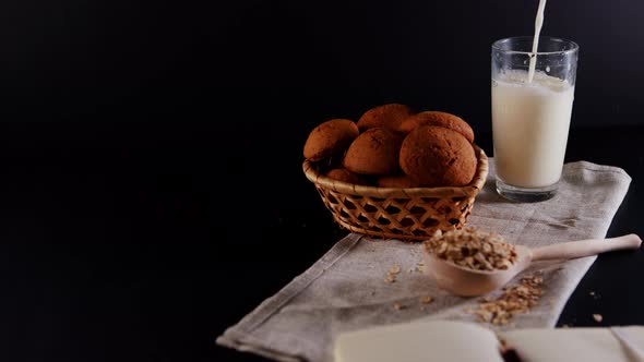 Basket of Fresh Oatmeal Cookies with Raw Oat Flakes in Large Wooden Spoon on Napkin on Black