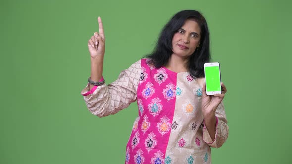 Mature Beautiful Indian Woman Showing Phone and Pointing Up