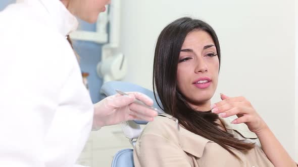 Close up of female patient talking with dentist and showing aching tooth