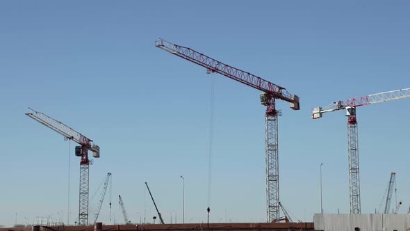 Tower cranes on a construction site against blue sky, Timelapse. Urban development concept