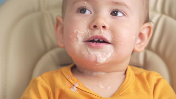 Toddler 12-18 months old eats oatmeal porridge and turns over his plate.