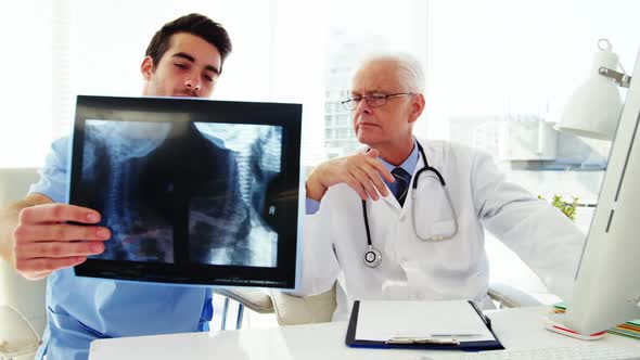 Male doctor and coworker examining x-ray