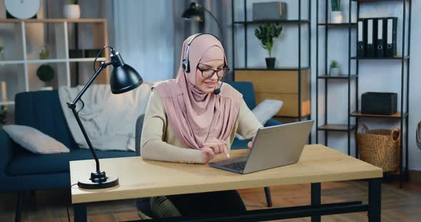 Arabic Woman in Hijab Sitting in front of Laptop in Headset During Online Video Conference