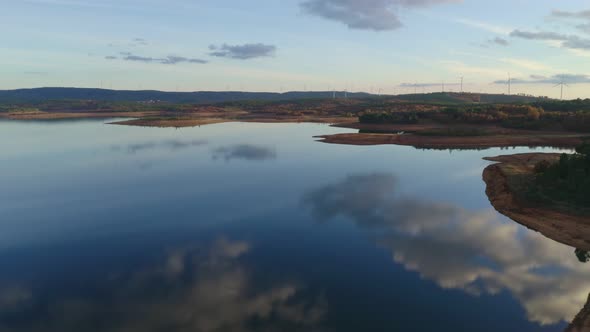 Drone aerial view of a lake reservoir of a dam with perfect reflection on the water of the sunset in