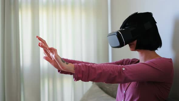 Woman using virtual reality headset in living room 