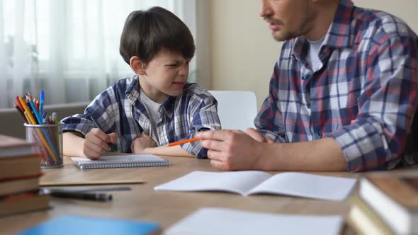 Dad Sitting at the Table and Making His Capricious Son to Do Homework, Education